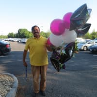 <p>George Ahmed carries congratulatory balloons for his son, Muhammad, one of Harrison High&#x27;s 246 graduates on Friday night at SUNY Purchase.
</p>