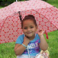 <p>A small girl watches the parade from under her umbrella.</p>