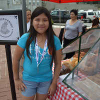 <p>A girl poses in front of the tent for Brewster Pastry at the Danbury Farmers Market. </p>