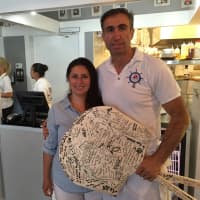 <p>Sammy Palik and his wife pose with two paddles signed by their customers at their eatery Monday afternoon. </p>