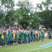 <p>Graduates throw their mortarboards in the air.</p>