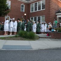 <p>Graduates wait to receive their diplomas.</p>