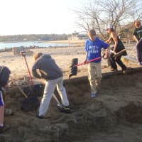 <p>Darien kids shovel away sand that was blown into the street in Noroton Bay.</p>