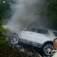 <p>A wrecked SUV smolders after firefighters doused its flaming front end Thursday. Its driver was rescued by a Westchester County police officer and HELP truck operator after she careened off the Spain Brook Parkway just south of the Eastview exit.</p>