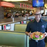 <p>Eveready&#x27;s Shawn Norman serves up a bacon cheeseburger at Eveready Diner in Brewster.</p>