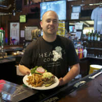 <p>Owner Ryan Healy of Healy&#x27;s Corner serves up one of his Bog Boy Burgers. The 10-ounce patty is topped with three cheeses, bacon, caramelized onions, and coleslaw.</p>