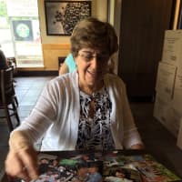 <p>Beth Cohen with photos of her clients over the years.</p>