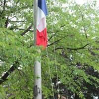 <p>Alexandre and Sabrina Sherman raise the French flag in New Rochelle.</p>