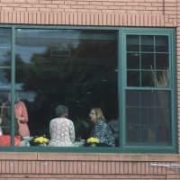 <p>People watch the concert from a window in a nearby building.</p>