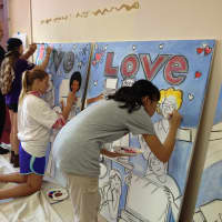 <p>Togetherhood volunteers with the Rye YMCA work with local artist Daniel DeNapoli on a triptych that will brighten the walls of the Don Bosco Community Center language and literacy center.</p>