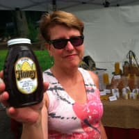 <p>Beekeeper Patty Heyl, of Redding, holds up a bottle of honey at the Wilton sidewalk sale.</p>