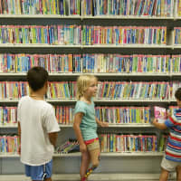 <p>Kids look at DVDs for sale at the Westport Library.</p>