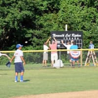<p>Norwalk players practice at Tim Devine Field as volunteers hang a banner donated by senior center members.</p>