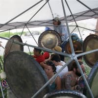 <p>People sit inside a circle of gongs meditating, as the gongs are repeatedly sounded. </p>