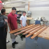 <p>Mauricio Agudero of Ossining, center, and Frank Corazao of New Rochelle, right, describe how many coats of stain will go on the trim that will decorate the exterior of Pope Francis&#x27; altar and pulpit being constructed by the teenagers at Lincoln Hall.</p>