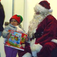 <p>Santa giving a young Port Chester girl a present at last year&#x27;s holiday kickoff event. </p>