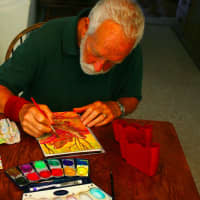 <p>John Newcomb uses a travel kit to create vibrant watercolors on display at Wilton Library in his Travels with John art exhibition.</p>
