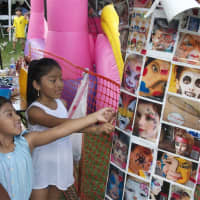 <p>Two young girls pick out face paintings at Sunday&#x27;s Ecuadorian Festival.</p>