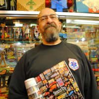 <p>Serious Toyz owner Tom Miano, stands with an ad in &quot;Antique Toy World&quot; magazine. The store will be on the cover of the industry publication in January.</p>