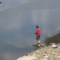 <p>A man fishes in the Amawalk Reservoir Sunday afternoon.</p>