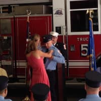 <p>New Wilton Firefighter John Edwards gets his badge pinned by his wife and daughter.</p>