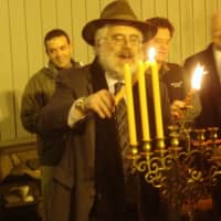 <p>Rabbi Yehoshua Hecht of Beth Israel of Westport and Norwalk continues lighting the menorah.</p>