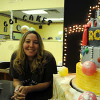 <p>Lynn Ayala, owner of Dream Cakes Bakery, stands with the Radio City Rockettes Christmas cake, from 2011. </p>