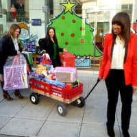 <p>Stamford TV host Trisha Goddard wheels out a wagon full of games and other toys that will be delivered to needy kids for the holidays. </p>