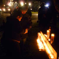 <p>A couple lights candles at the vigil outside Saint Rose of Lima Catholic Church during the vigil. </p>