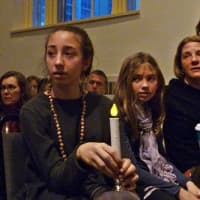 <p>Lulu Busk, 13, her sister Bella, 10 and their mother, Andrea, sit with candles at the Westport memorial service Sunday evening to remember the victims of the Sandy Hook Elementary School shooting.</p>