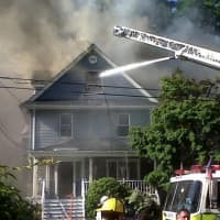 <p>Firefighters attempt to extinguish an Elmsford fire that destroyed one home and jumped to the next on Woodside Avenue in June.</p>