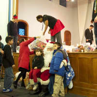 <p>New Rochelle children take turns with Santa as helpers hand out toys.</p>