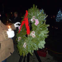 <p>A Yorktown resident pins the name of Sandy Hook victim onto a wreath.</p>