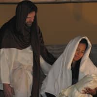 <p>Volunteer actors dressed as Joseph and Mary cradle a facsimile of a newborn Jesus inside the stable at Eastchester Community Church.</p>