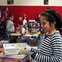 <p>Fifth-grader Isabel Trinkaus helps her teachers set up for the tag sale at Scoland Elementary School in Ridgefield. She said looks forward to being a pen pal with a student at P.S. 104.</p>