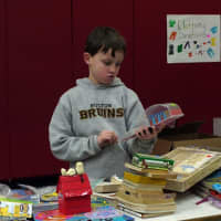 <p>Fifth-grader Drew Fortsen, 11, helps to set up the tag sale but also takes a look around at the merchandise.</p>
