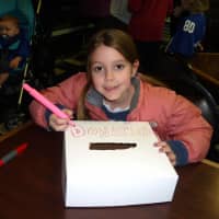 <p>Caroline Motyl, daughter of resident Sarah Green, creates a box for donations at Great Cakes Wednesday.</p>