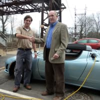 <p>From left, Nate Roumanis of Encon Solar congratulates Westport Building Official Stephen Smith Monday after Smith successfully charges his Tesla using one of the new car-charging stations.</p>