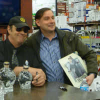 <p>Actor Dan Aykroyd poses for a picture with a fan and signs a bottle of his Crystal Head vodka.</p>