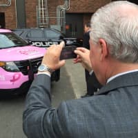 <p>First Selectman Michael Tetreau snaps a photo of the pink police cruiser following its unveiling Monday.</p>