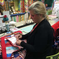 <p>A volunteer sews the finishing touches on a quilt.</p>