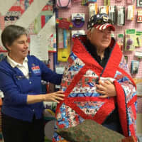 <p>Jane Dougherty, the Connecticut representative for Quilts of Valor, left, wraps a veteran in his quilt.</p>