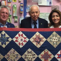 <p>Norwalk Mayor Harry Rilling, left, and his wife, Lucia, right, present a quilt at Christie&#x27;s Quilting Boutique in Norwalk on Saturday.</p>