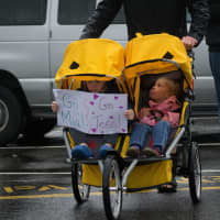 <p>Two children keep dry as their mother pushes them in a running stroller in Sunday&#x27;s Run Like A Mother 5k in Ridgefield.</p>