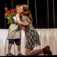 <p>An outgoing Sleepy Hollow High School senior receives a hug and a rose from a first-grader during a special goodbye ceremony.</p>