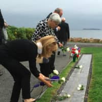<p>Family members place white roses on the names of those who died in the 9/11 attacks during the ceremony Thursday evening in Westport.</p>