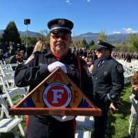 <p>A firefighter holds the flag that was presented to the Saunders family at the ceremony.</p>