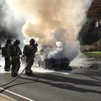 <p>Firefighters extinguish a car fire on White Plains Road in Trumbull on Friday morning.</p>