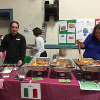 <p>Parents serve food at the Italian table at ACS Eats.</p>