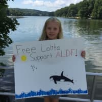 <p>Willow, 8, of Ringwood, stands in front of the lake she&#x27;ll swim across for Lolita on Aug. 16, her birthday.</p>